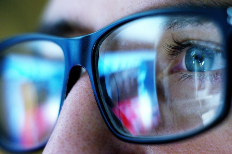 Close no olho de um pentester que utiliza óculos refletindo telas.
